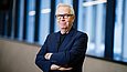 Architekt David Chipperfield vor einem architektonischen Hintergrund.