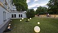 Mit leuchtenden Kugeln illuminierte Rasenfläche einer weißen Villa