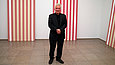 Mann steht in einem Raum mit rot-weiß gestreiften Ausstellungsobjekten