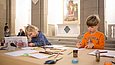Zwei Kinder sitzen an einem Tisch mit Bastelutensilien