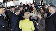 Mehrere Menschen umringen eine Frau und einen Mann, die in einer Rückenansicht zu sehen sind