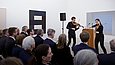 Zwei stehende Violinistinnen spielen vor sitzendem Publikum