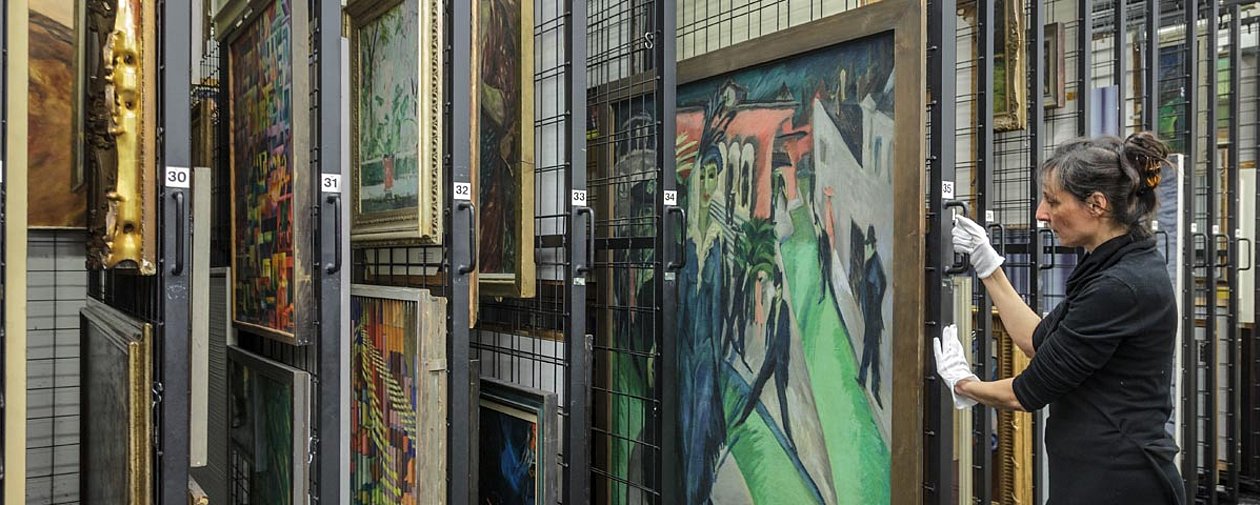 Frau im Depot der Neuen Nationalgalerie neben einem Gemälde