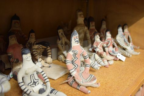 Several humanoid clay figures sit on a depot shelf