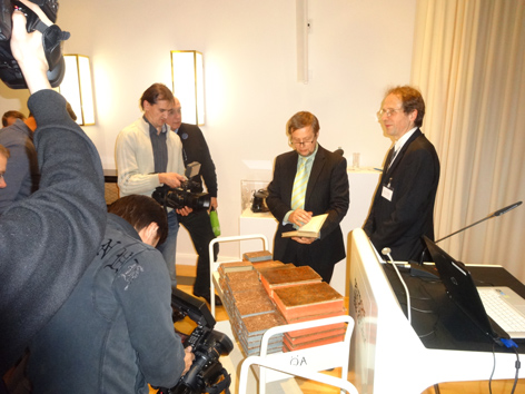 DRBD Mehrere Menschen betrachten Bücher auf einem Bücherwagen und werden dabei fotografiert.