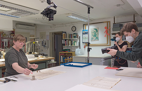 Dagmar Jankewitz A woman is working on a historical document at a table and is photographed by two people.