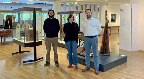 Three people pose for a photo in a musical instrument exhibition