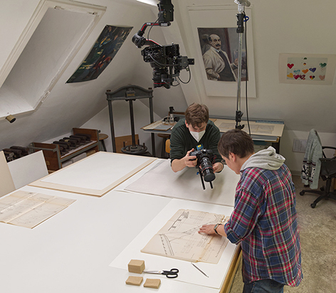 Eine Person fotografiert eine andere, die ein historisches begutachtet.