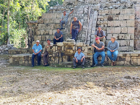 Forschungsfragen: Team Gruppenfoto vor einem verwitterten Gebäude im Grünen
