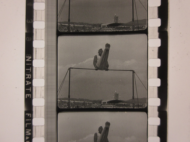 Negative of a photograph showing a man performing gymnastics on the horizontal bar