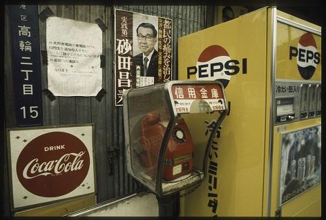 Wand mit Plakaten, einer Telefonzelle und einem Getränkeautomaten
