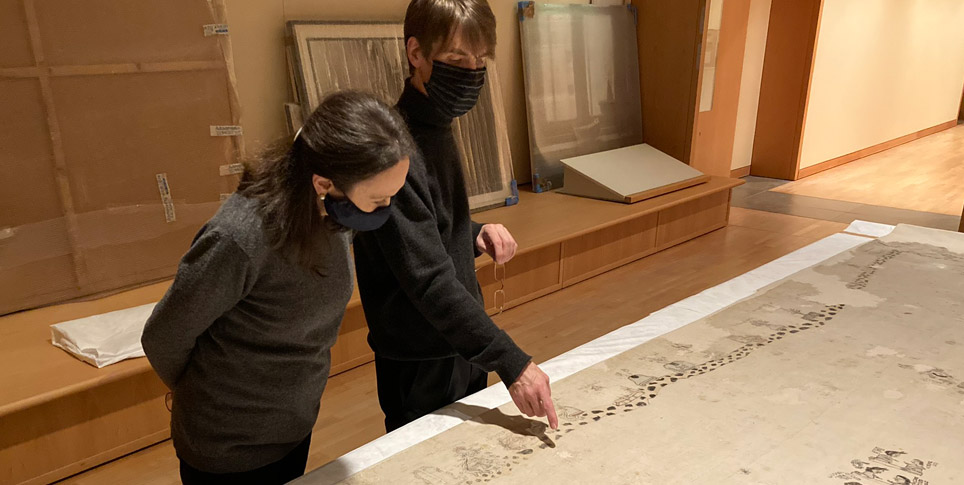 Flemming and Arens with the Lienzo Seler II Two people view a historical cotton cloth laying flat on a large table