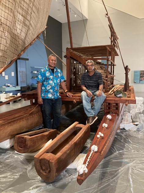 [Translate to English:] Zwei Männer sitzen auf einem hölzernen Segelboot in einem Museumsraum