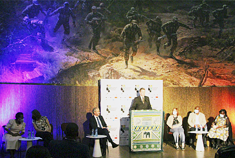 Pressekonferenz anlässlich der Ankunft der 23 Objekte im Independence Memorial Museum Redner auf einem teppichbehängtem Podium vor überdimensioniertem Wandbild, das bewaffnete Soldaten zeigt, links und rechts neben ihm sitzend jeweils drei weitere Personen