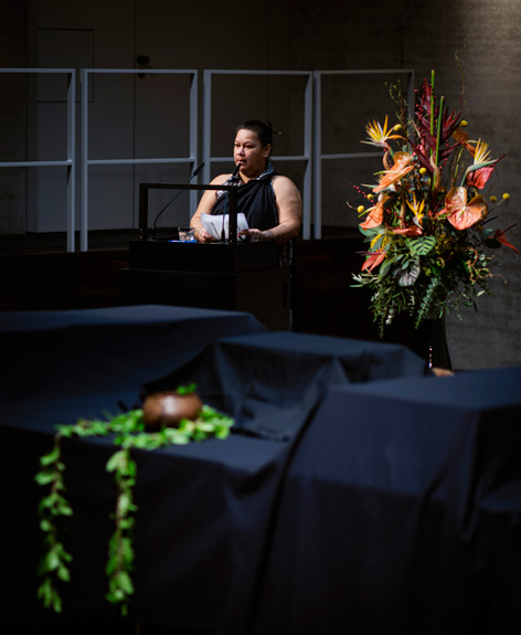 Kalehua Kamoali‘i Caceres A woman speaks at the ceremony, there is a table covered with black cloth