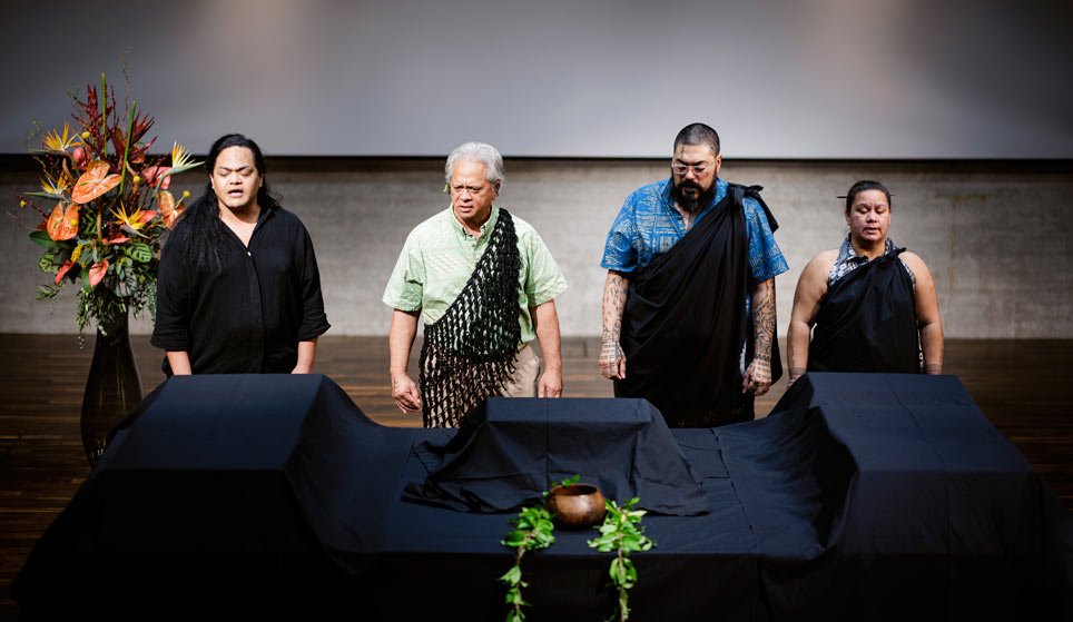 Ceremony Four people stand with their eyes closed in front of a table covered with a black cloth