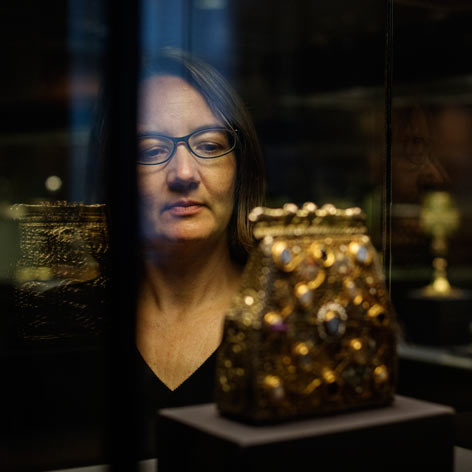 A woman looks at a reliquary in a glass case