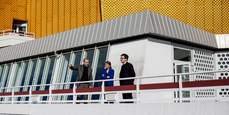 Three people standing on the terrace of a modern building