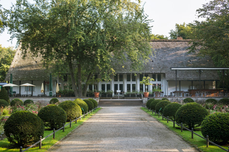 Tiergarten Blick auf einen von Büschen gesäumten Weg zu einem Gebäude.
