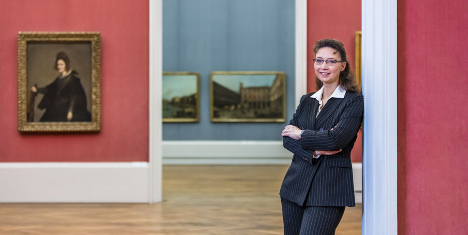 A woman stands in a museum with paintings