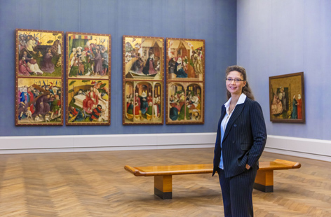 Dagmar Hirschfelder Eine Frau steht in einem Ausstellungsraum mit mittelalterlichen Gemälden