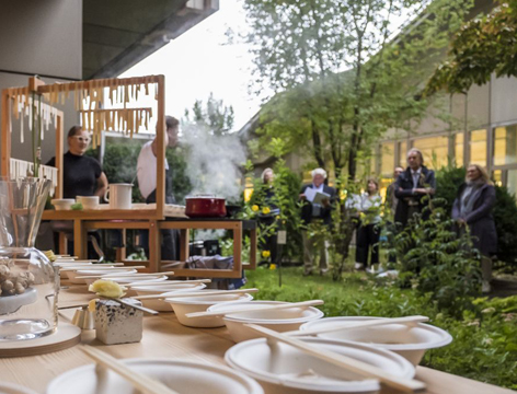 Gedeckte Tafel und Menschen im grünen Innenhof eines brutalistischen Baus