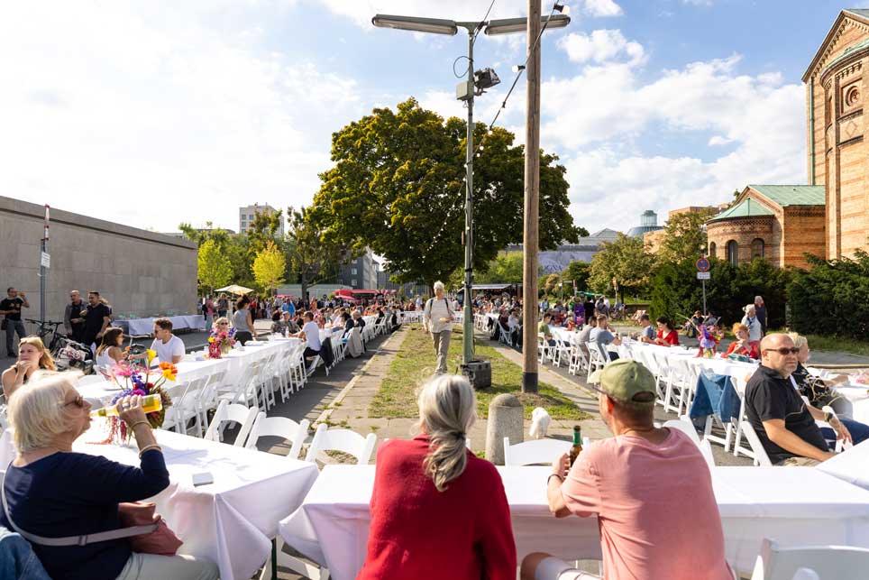 Diese gigantische Tafel ist eigentlich eine Demonstration für mehr Museumsgärten © Stefanie Heider Menschen essen und reden an einem langen Tafeloval im Freien