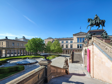 View of the green colonnaded courtyard of the Museum Island with historic buildings.