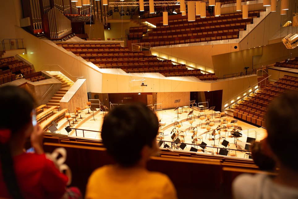 Blick in einen Konzertsaal, im Vordergrund Hinterköpfe von Personen