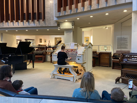 A woman plays a cinema organ in a museum