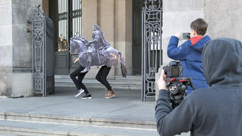 lab.Bode-Finale: Objekte raus aus Museum Pappferd mit menschlichen Beinen trabt aus Museum, fotografiert von zwei MEnschen