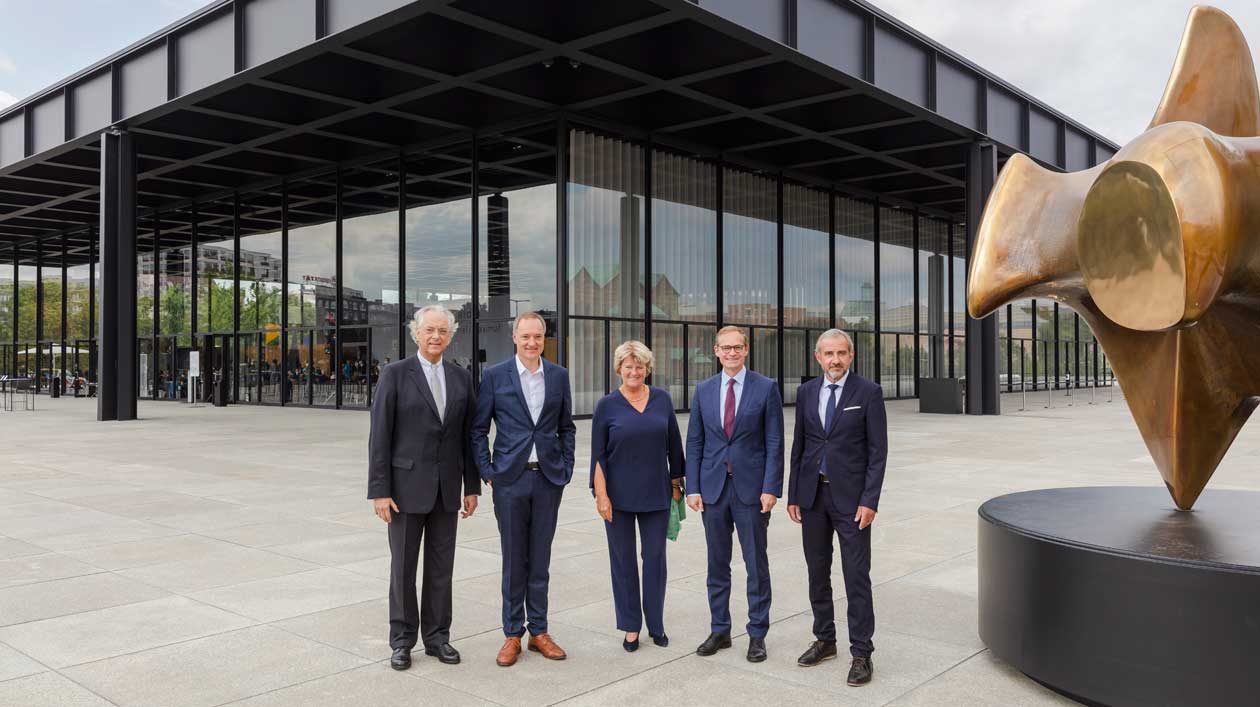 Fünf Personen posieren vor einem modernen Gebäude aus Glas und Stahl