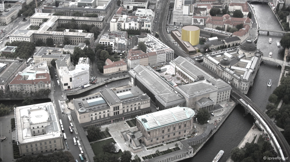 Luftbild eines Stadtraums mit Prachtbauten, in das die computergenerierte Visualisierung eines modernen Ausstellungshauses eingefügt ist
