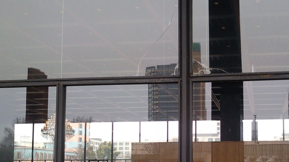 Close-up of the glass facade with heavy damage from broken glass (opens enlarged image)