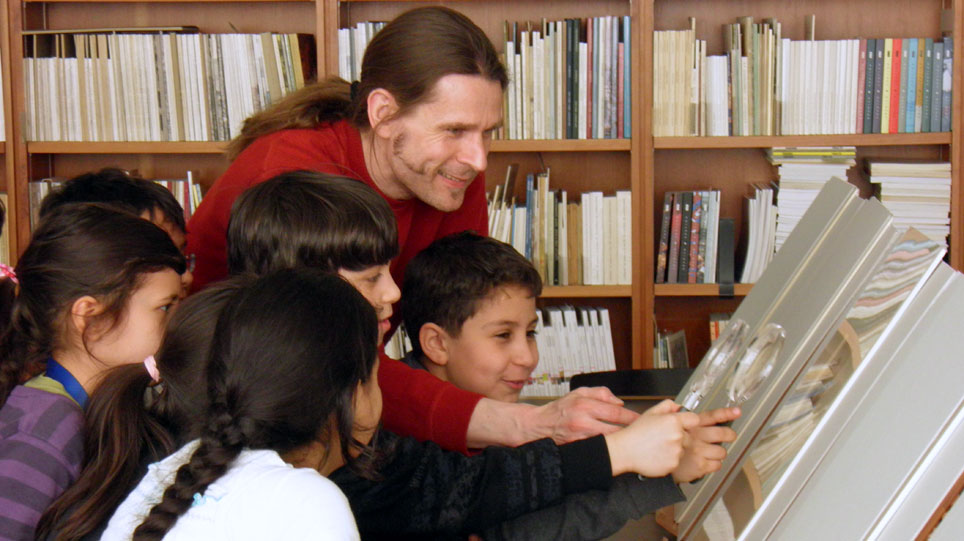 A man shows illustrations in a book to several children