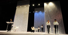 Mehrere Personen führen eine szenische Lesung auf einer Bühne auf
