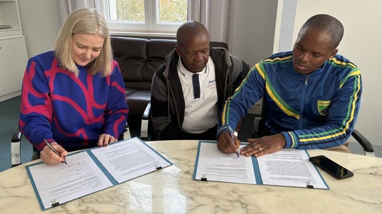 Nachfahren von Mangi Molelia in Berlin Drei Personen sitzen an einem Tisch und unterzeichnen Dokumente bei einem Treffen in Berlin.