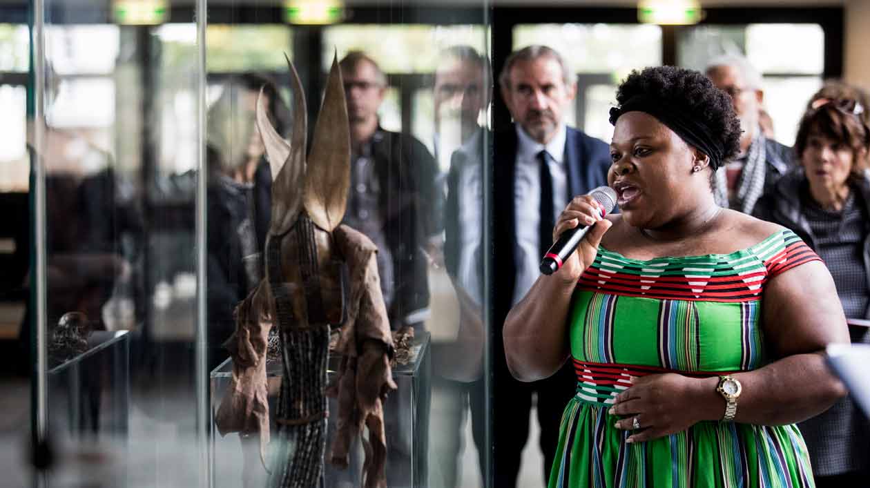 Präsentation der Kooperation des Ethnologischen Museums mit der Museums Association of Namibia Eine Frau erklärt ein Objekt, das in einer Vitrine liegt