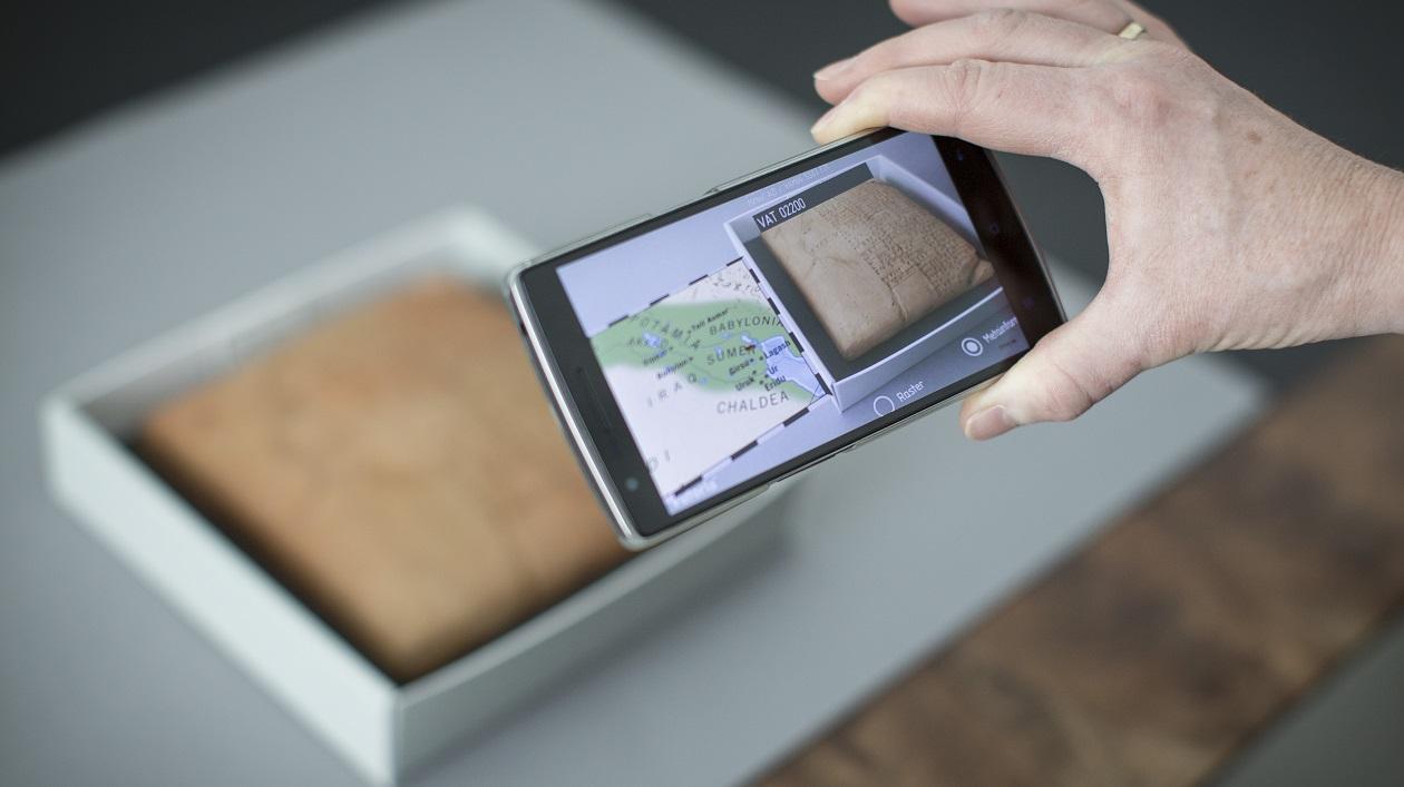 Smartphone wird über ein archäologisches Objekt gehalten