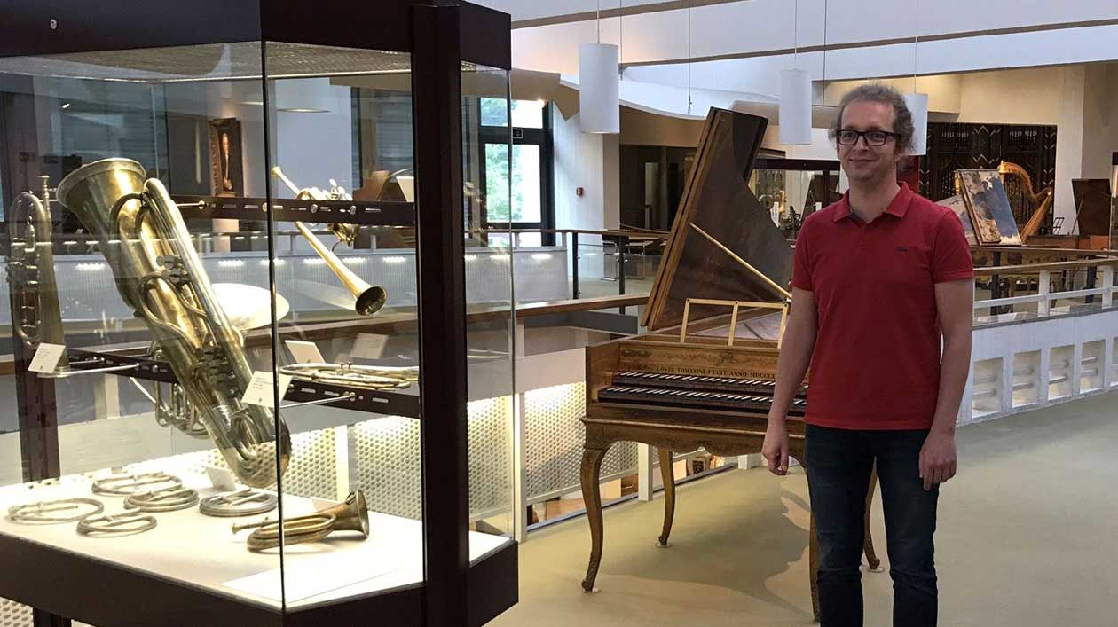 Christian Breternitz next to a showcase with wind instruments