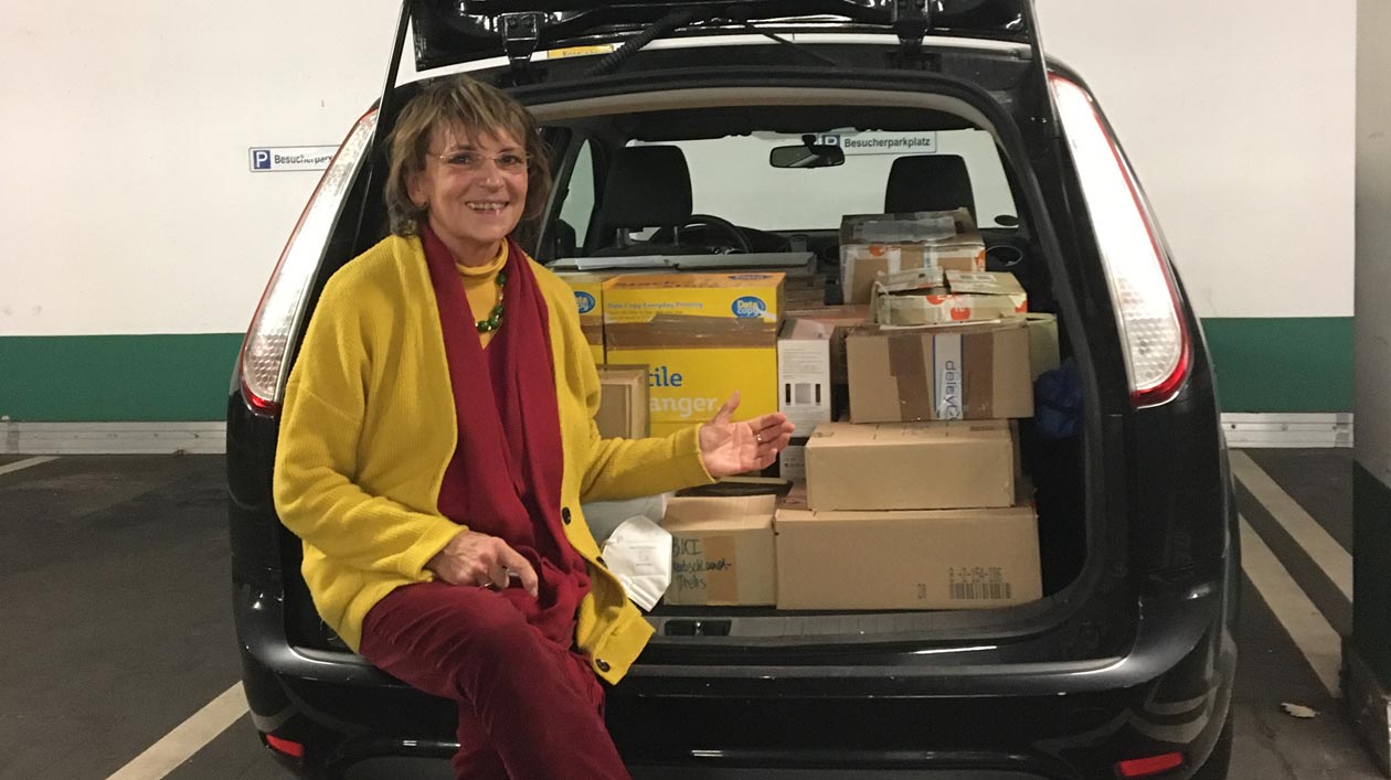 Carola Wedel Eine Frau sitzt in einem Kofferraum voller Kartons