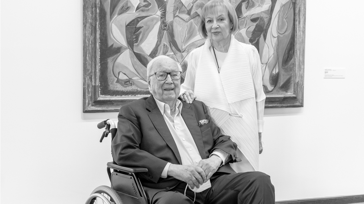 Älterer Herr im Rollstuhl und ältere Dame vor modernem Kunstwerk