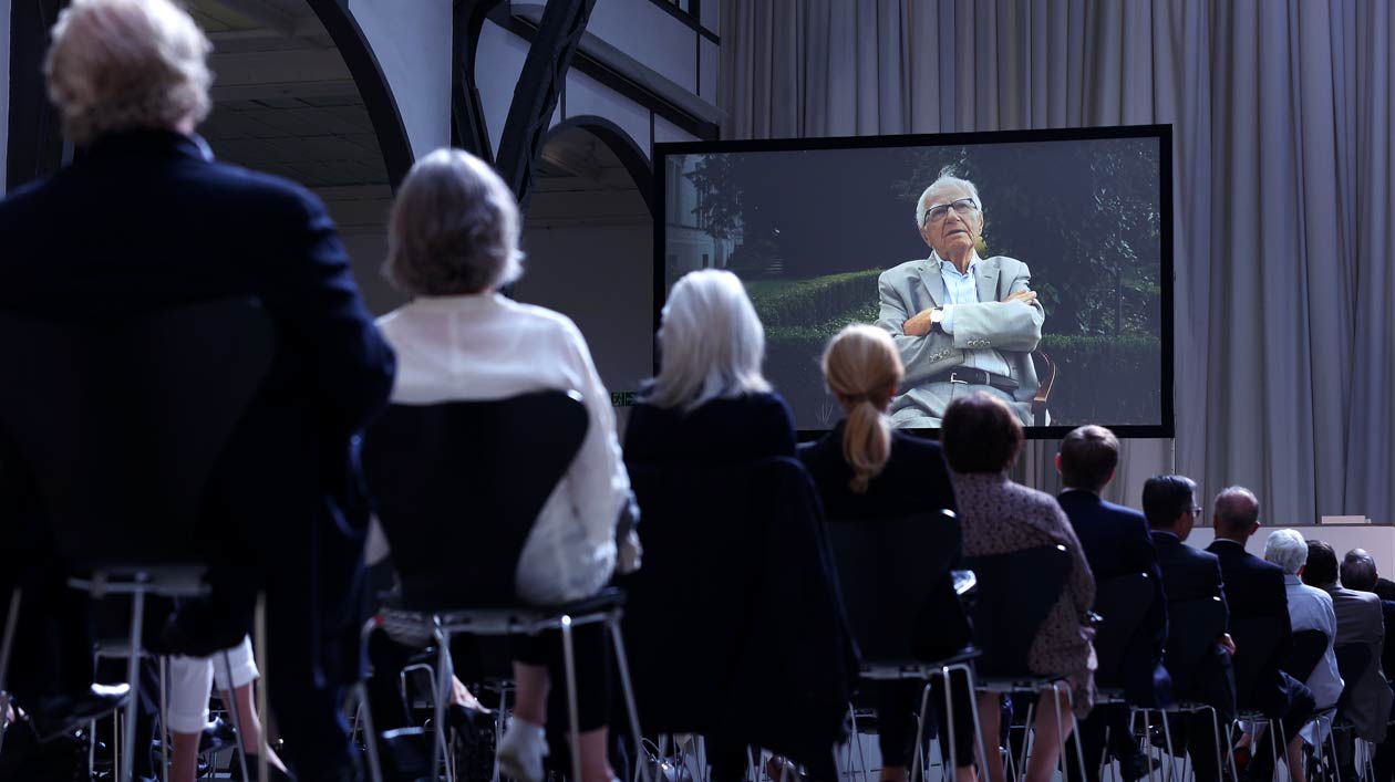 Guests of the commemoration watch a film about Erich Marx on the screen.