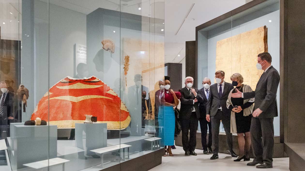 A delegation in an exhibition hall of the Ethnological Museum in the Humboldt Forum with high showcases.