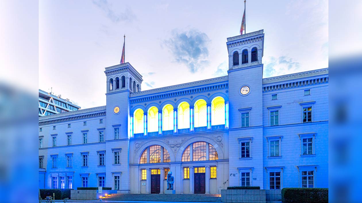 Blau illuminiertes Bahnhofsgebäude mit heller Fassade