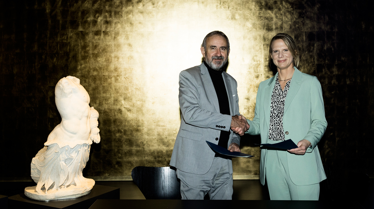 ZDF Medienpartnerschaft: SPK-Präsident Hermann Parzinger und Programmdirektorin Nadine Bilke Mann und Frau schütteln sich die Hand, links eine Skulptur