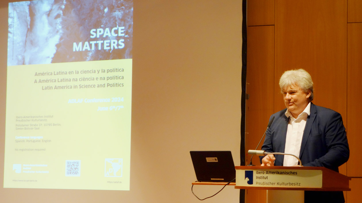 Tagung der Arbeitsgemeinschaft Deutsche Lateinamerikaforschung (ADLAF) im IAI, 6.-7.6.2024 Ein Redner steht an einem Podium, hinter ihm wird eine Präsentationsfolie an die Wand projiziert