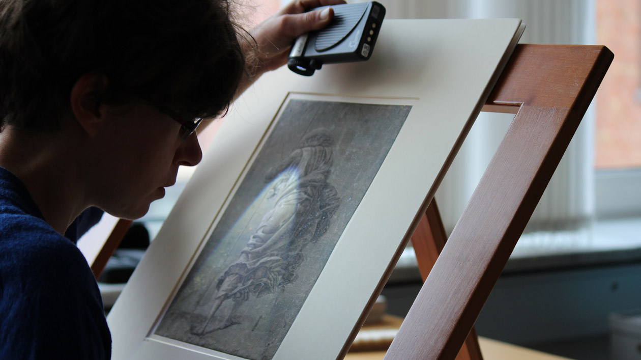 Eine Frau untersucht ein historisches Bild mit einem Spezialgerät