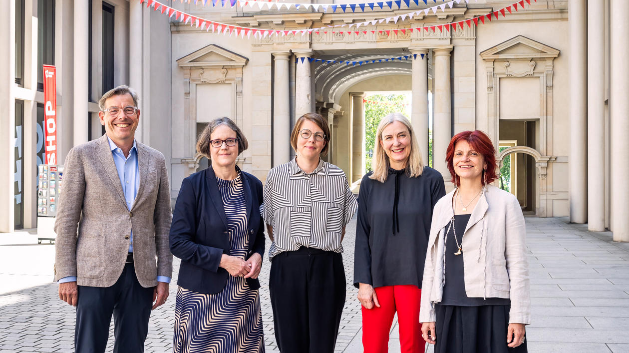 Fünf Personen posieren für ein Gruppenbild in einem bewimpelten Schlosshof